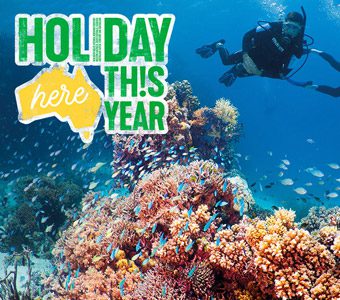 Diver swimming over a colourful coral on Australia's great barrier reef with a banner reading: holiday here this year
